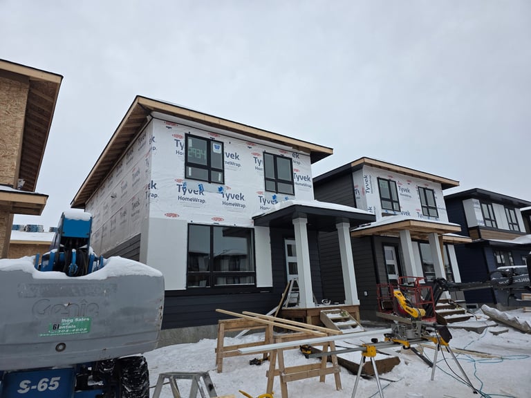 New residential homes under construction in winter with construction equipment and materials on snowy ground