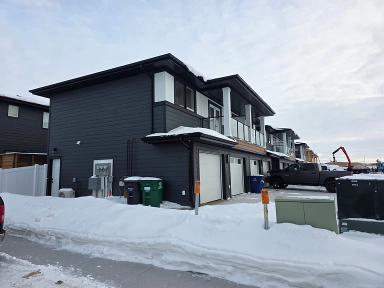 Modern black townhouse in snowy winter setting with white trim, covered in fresh snow